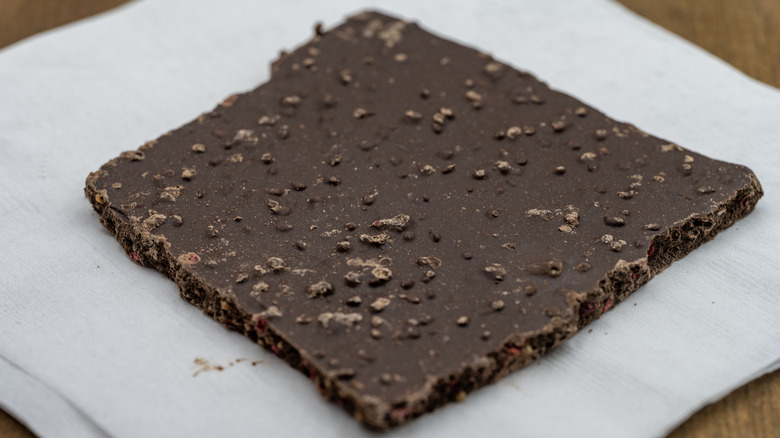 A piece of dark chocolate bark on wax paper