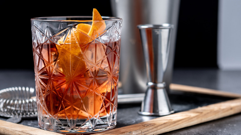 An Old Fashioned cocktail in a decorative glass on a serving tray