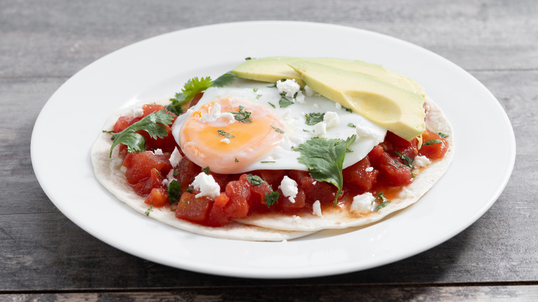 An elegant plate of huevos rancheros in a white dish