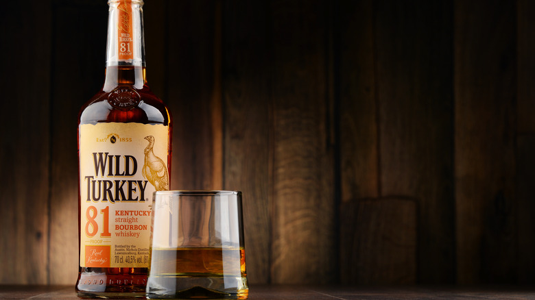 Bottle of Wild Turkey next to glass of bourbon