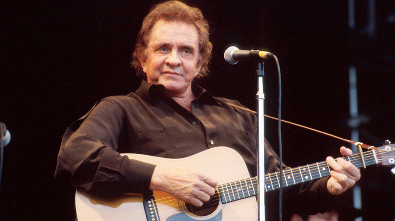 Johnny Cash playing acoustic guitar on stage