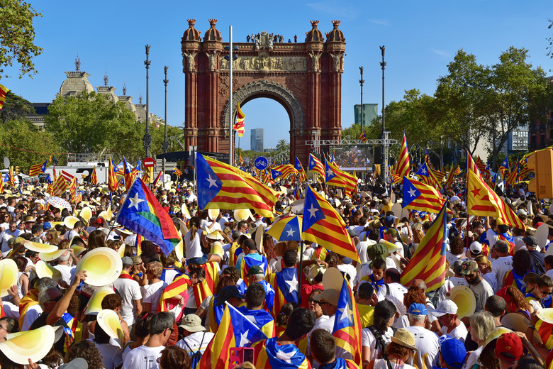A crowd waves Catalan flags in a public square.