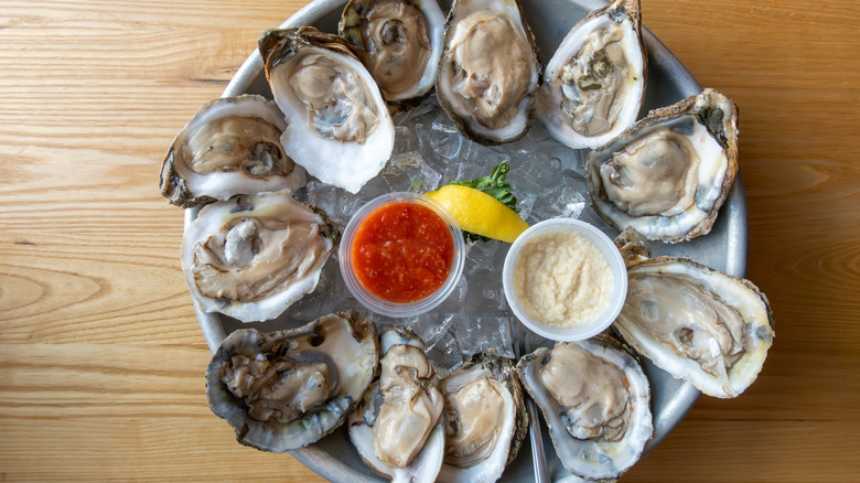 Platter of oysters on the half shell over ice served with cocktail sauce and mayonnaise