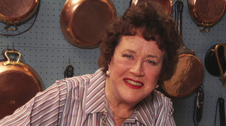 Close-up of Julia Child in front of her wall of copper cookware