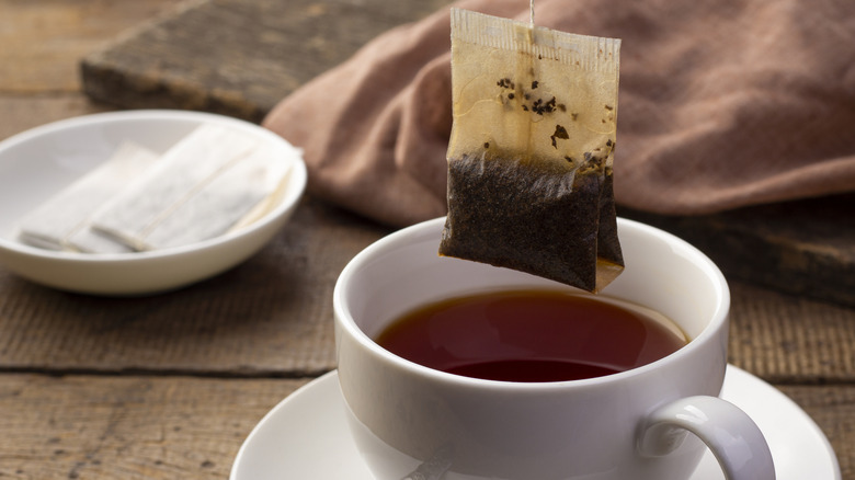 Teabag hanging over a white cup of tea