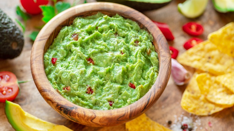 Fresh guacamole in a bowl surrounded by chips