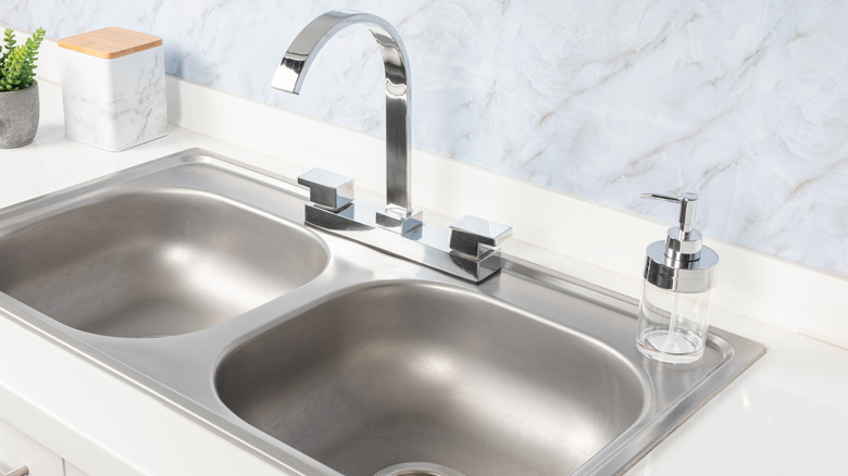 Stainless steel kitchen sink in white countertop