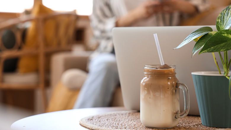jar of iced latte next to a laptop