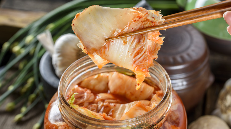 removing a piece of kimchi from jar with chopsticks