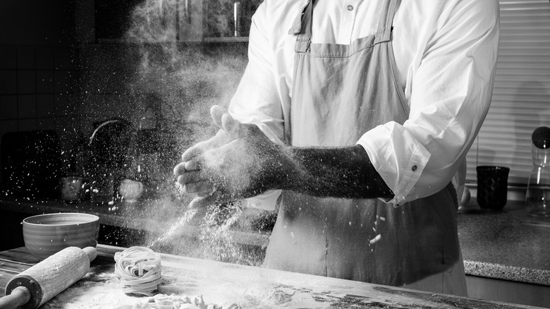 A man makes pasta with an apron on