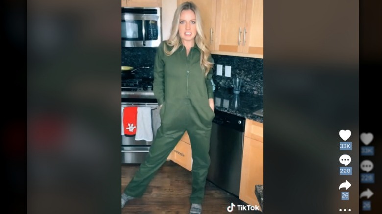 A woman wears a green jumpsuit in a kitchen