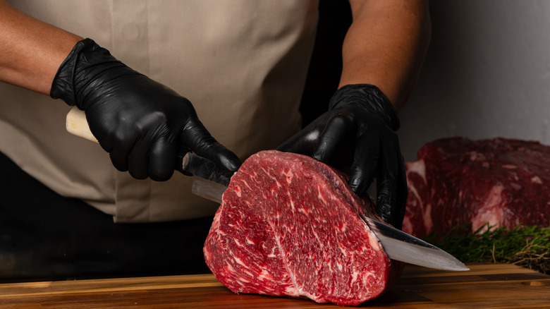 A chef slicing a large cut of beef