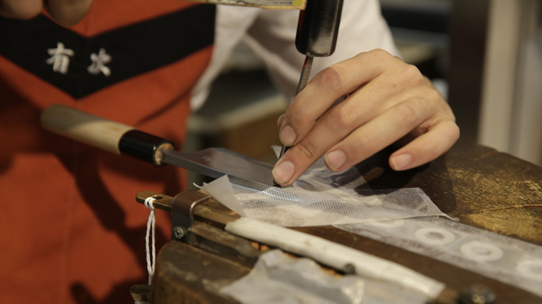 A Japanese knife maker working on a blade