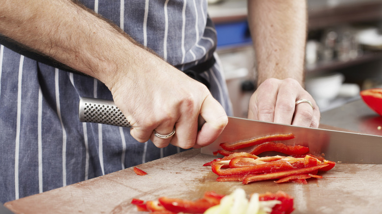 A chef chopping red peppers