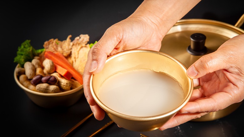 Hand holding a bowl of makgeolli