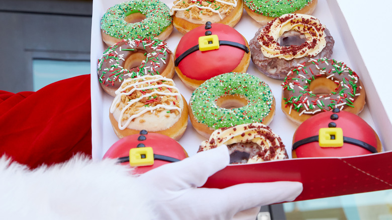 santa gloves holding box of Krispy Kreme Christmas donuts
