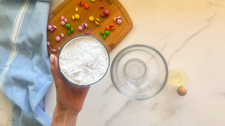 hand adding sugar to bowl