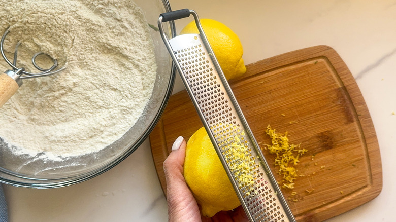 hand zesting lemon over board