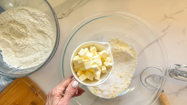 hand adding butter to bowl