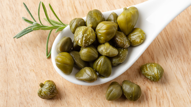 Spoonful of capers on wooden table