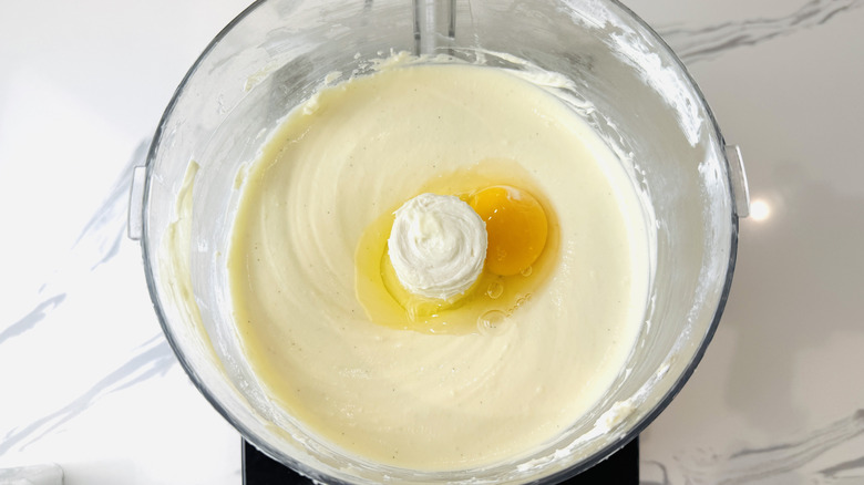 Adding eggs to cheesecake batter in food processor