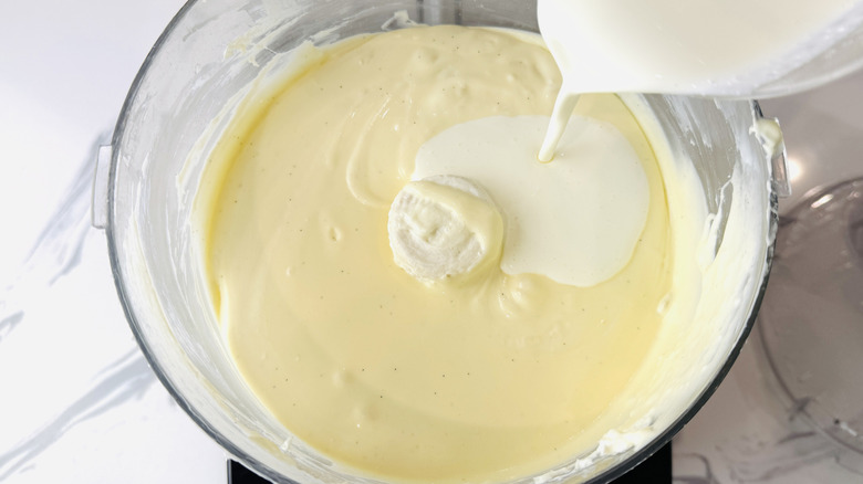 Pouring cream into cheesecake batter in food processor