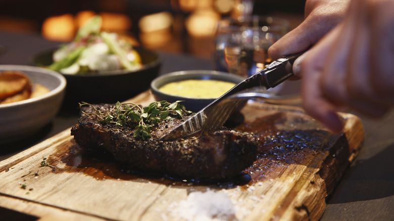 Man cutting through steak at restaurant