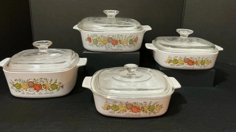 An 8 piece CorningWare set with 4 clear lids and 4 casseroles with colorful vegetable designs