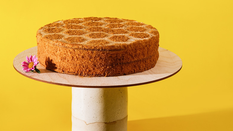 A traditional honey cake sits on an elevated platform against a yellow background