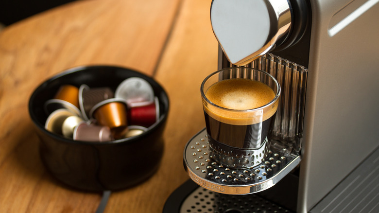 A glass of brewed coffee sitting on Nespresso machine