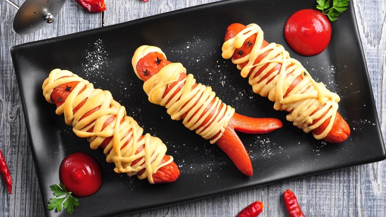 Mummy hot dogs on a black plate
