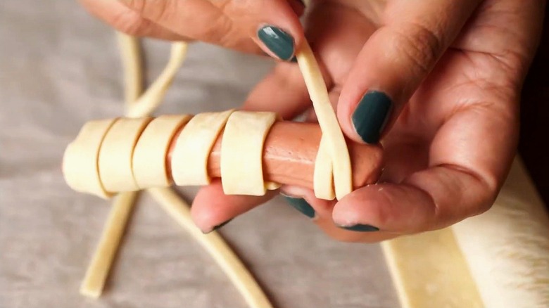 Close-up of wrapping crescent roll dough around a hot dog