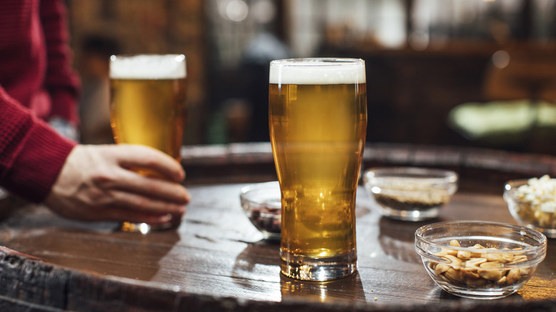 A glass of beer and bowl of peanuts