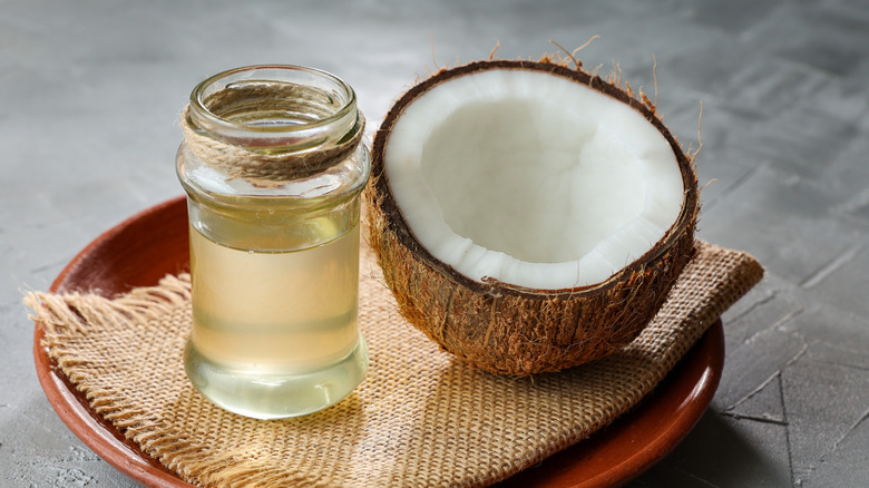 Half of a coconut and jar of coconut oil