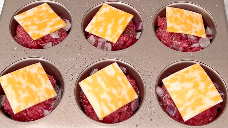 Sliders topped with cheese in muffin pan