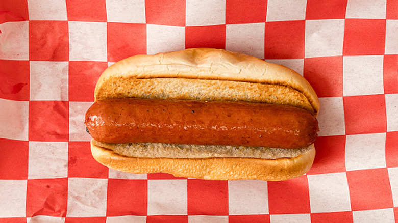A plain hot dog on red and white checkered paper.