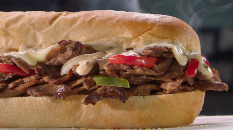 Closeup of a Jersey Mike's cheesesteak with white American cheese, peppers, and onions