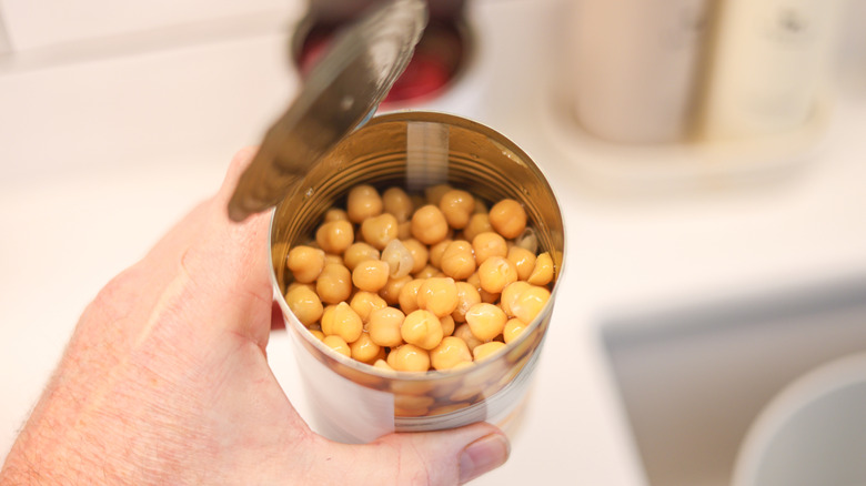 Hand holding open can of chickpeas