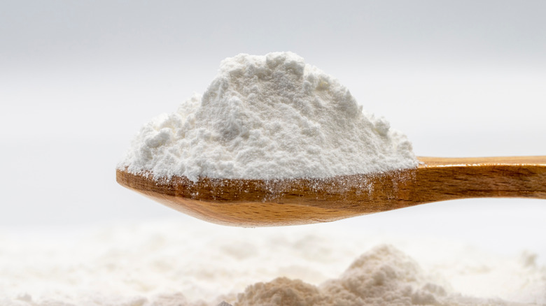 Close-up of a heap of powdered sugar on a wooden spoon with more powdered sugar underneath