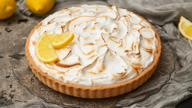 A lemon meringue pie with a short crust topped with two lemon slices