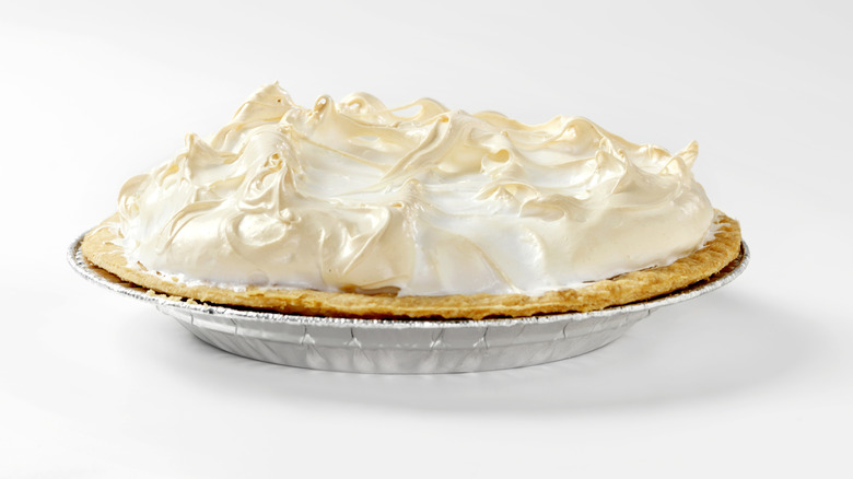 A lemon meringue pie in a silver pie pan isolated on a white background
