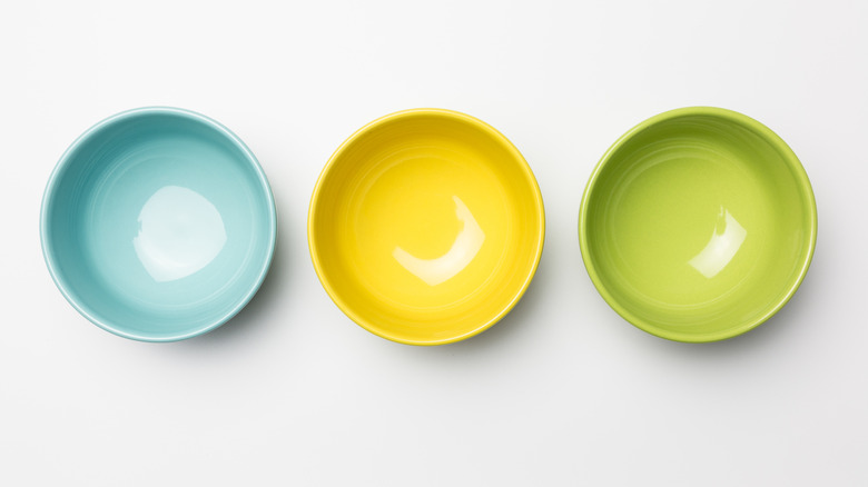 Three brightly colored bowls in blue, yellow, and green arranged in a line