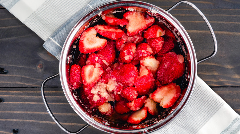 Macerated strawberries in a steel bowl placed on a wooden table