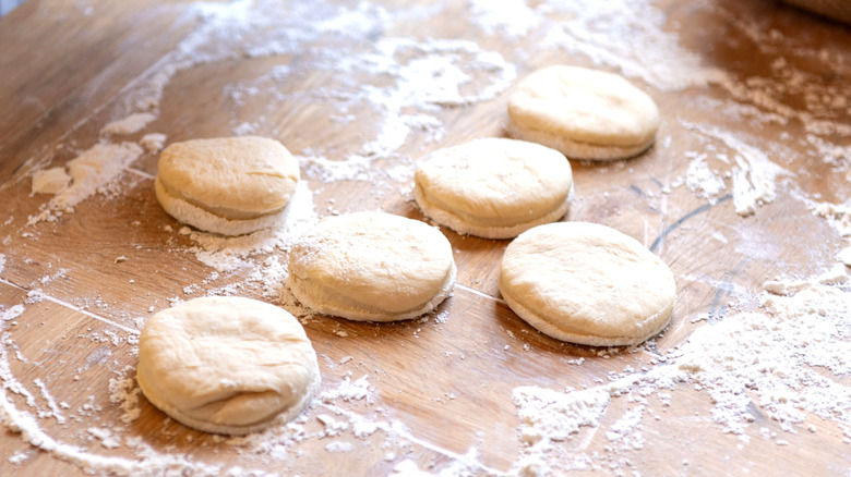 Unbaked shortcakes on a wooden table dusted with flour