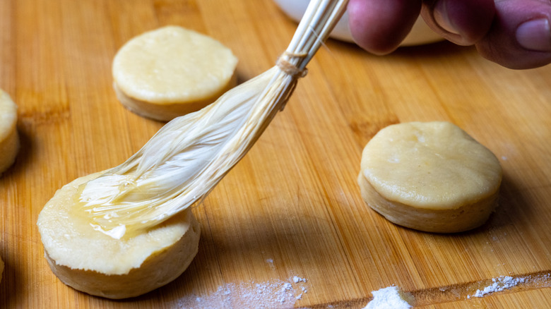 A person brushing shortcakes using a pastry brush