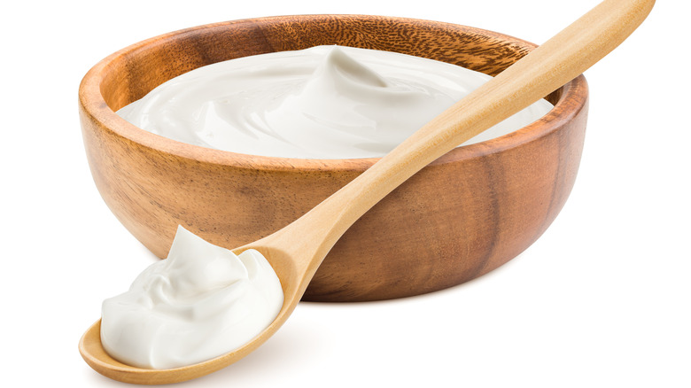 A wooden bowl and spoon of sour cream