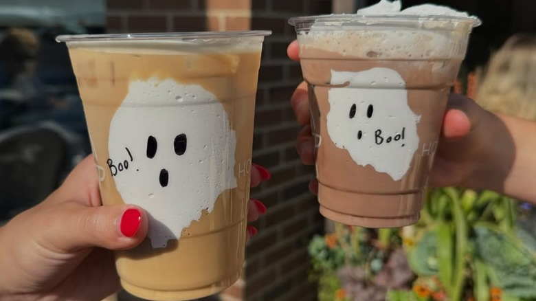 two hands holding ghost lattes
