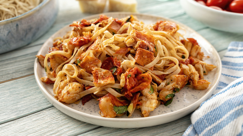 Lobster pasta with herbs and tomatoes in it.