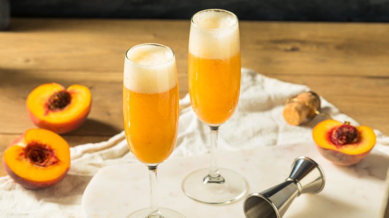 Peach Bellini in flutes with peaches and cork