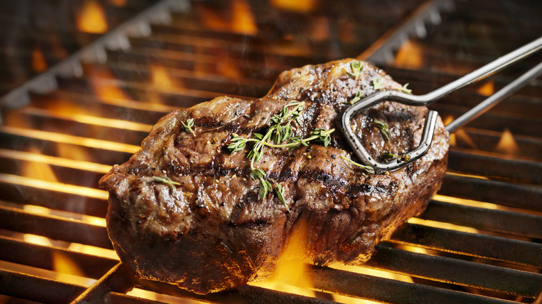 grilling a steak over flame